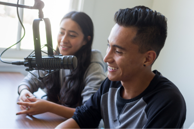 Students speak in microphone in a podcast studio